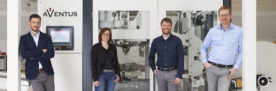 AVENTUS Team vor einer Verpackungsmaschine in der Produktionshalle
