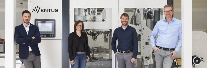 AVENTUS Team vor einer Verpackungsmaschine in der Produktionshalle