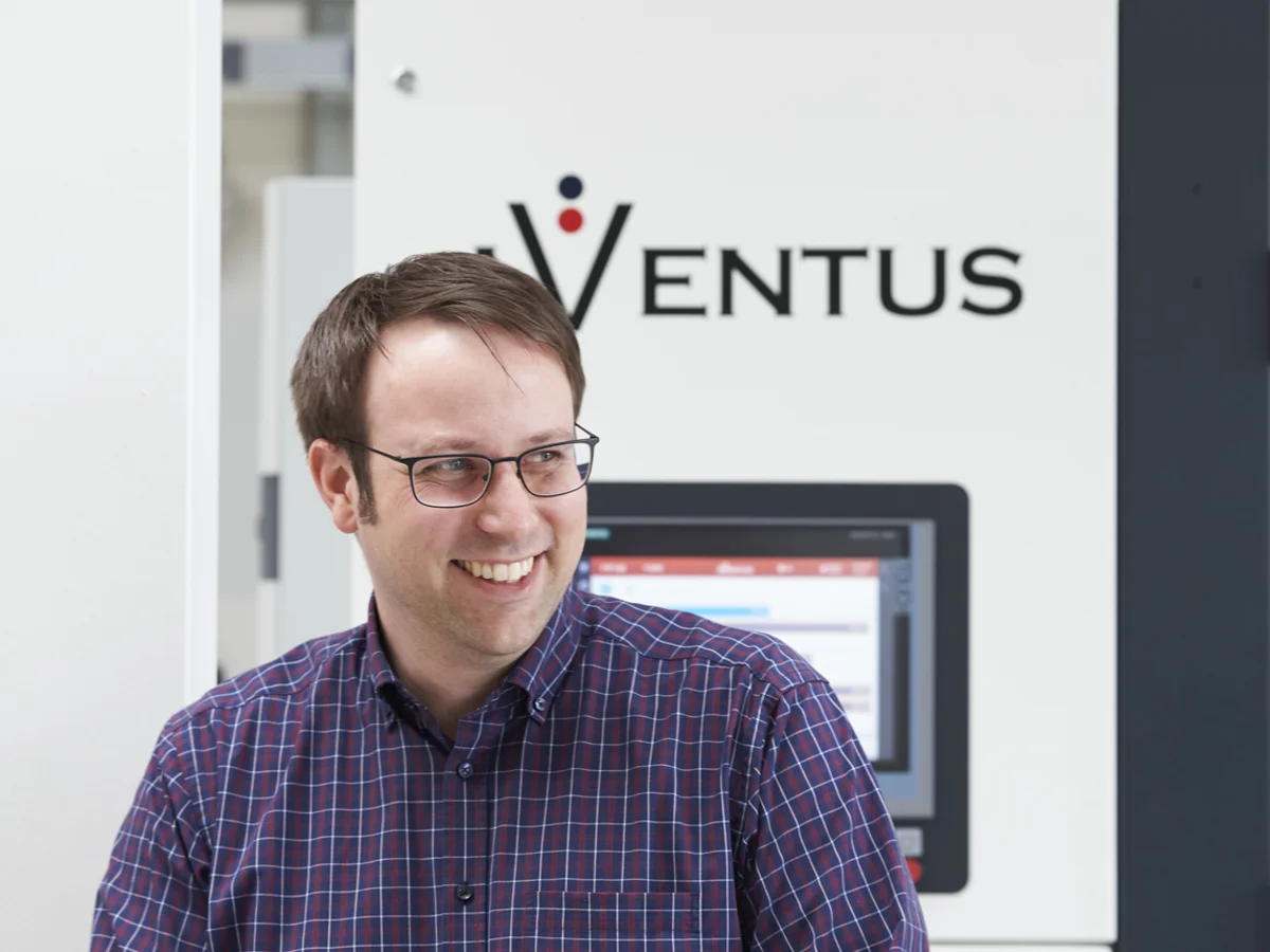 AVENTUS-Mitarbeiter vor einer AVENTUS Verpackungsmaschine in der Produktionshalle
