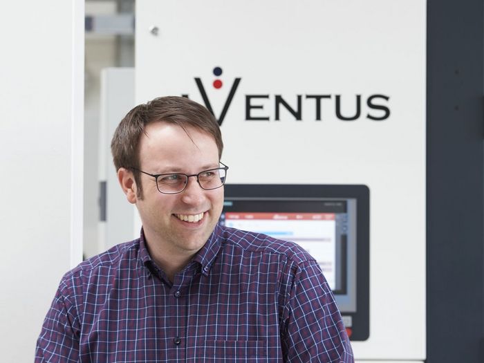 AVENTUS-Mitarbeiter vor einer AVENTUS Verpackungsmaschine in der Produktionshalle