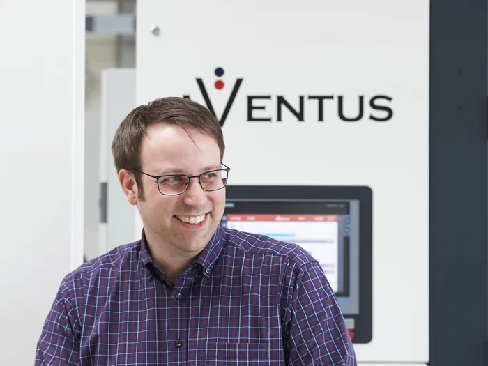 AVENTUS-Mitarbeiter vor einer AVENTUS Verpackungsmaschine in der Produktionshalle