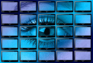 Surveillance cameras show a close-up of a human eye on 25 screens, symbolizing visual control and video surveillance.